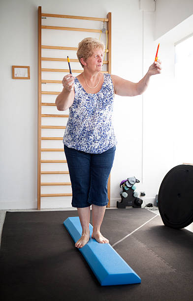 Physiotherapist, vestibular rehabilitation on patients who are suffering from vertigo, balance disorders, relating to the inner ear. A patient does some exercises for balance. (Photo by: BSIP/Universal Images Group via Getty Images)